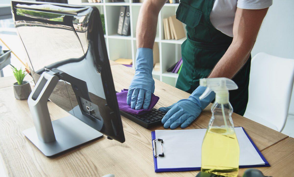 office cleaner wiping down computer keyboard