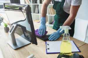 office cleaner wiping down computer keyboard