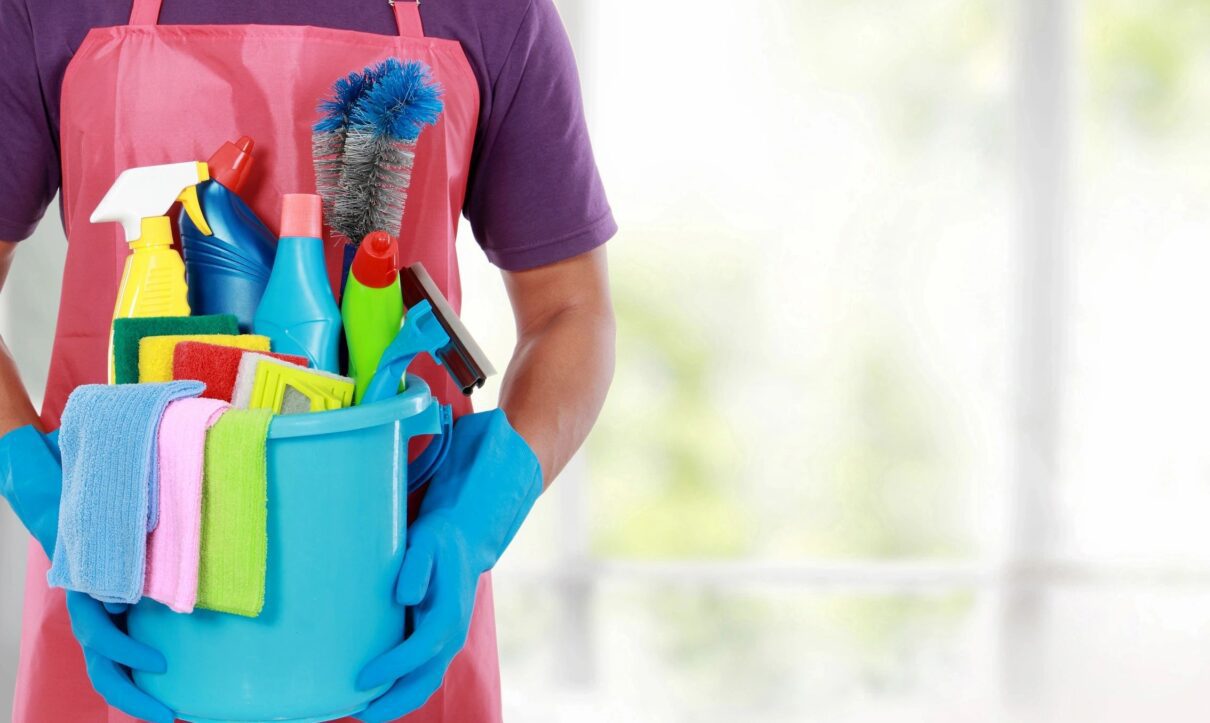 commercial cleaner holding a bucket of cleaning products